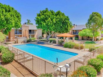 A large swimming pool surrounded by a fence and trees.